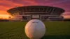 AT&T Stadium in Arlington with official World Cup soccer ball on turf at sunset