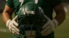 NFL Jets offensive lineman holding helmet in professional stadium setting