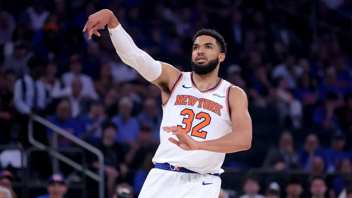 Karl-Anthony Towns in a New York Knicks jersey making a shooting gesture on the court.