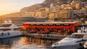 Monaco Grand Prix paddock with Ferrari garage and luxury yachts in harbor at golden hour