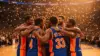 Knicks players celebrating together in team huddle after NBA championship victory with confetti falling