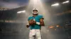 NFL quarterback in Dolphins uniform under dramatic spotlight in empty stadium showing pressure and scrutiny