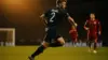 Scottish footballer in navy jersey making attacking run during World Cup match under stadium lights