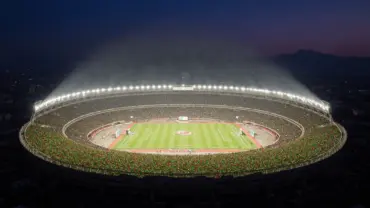 Estadio Azteca illuminated at night during World Cup match with packed crowd and mountain backdrop