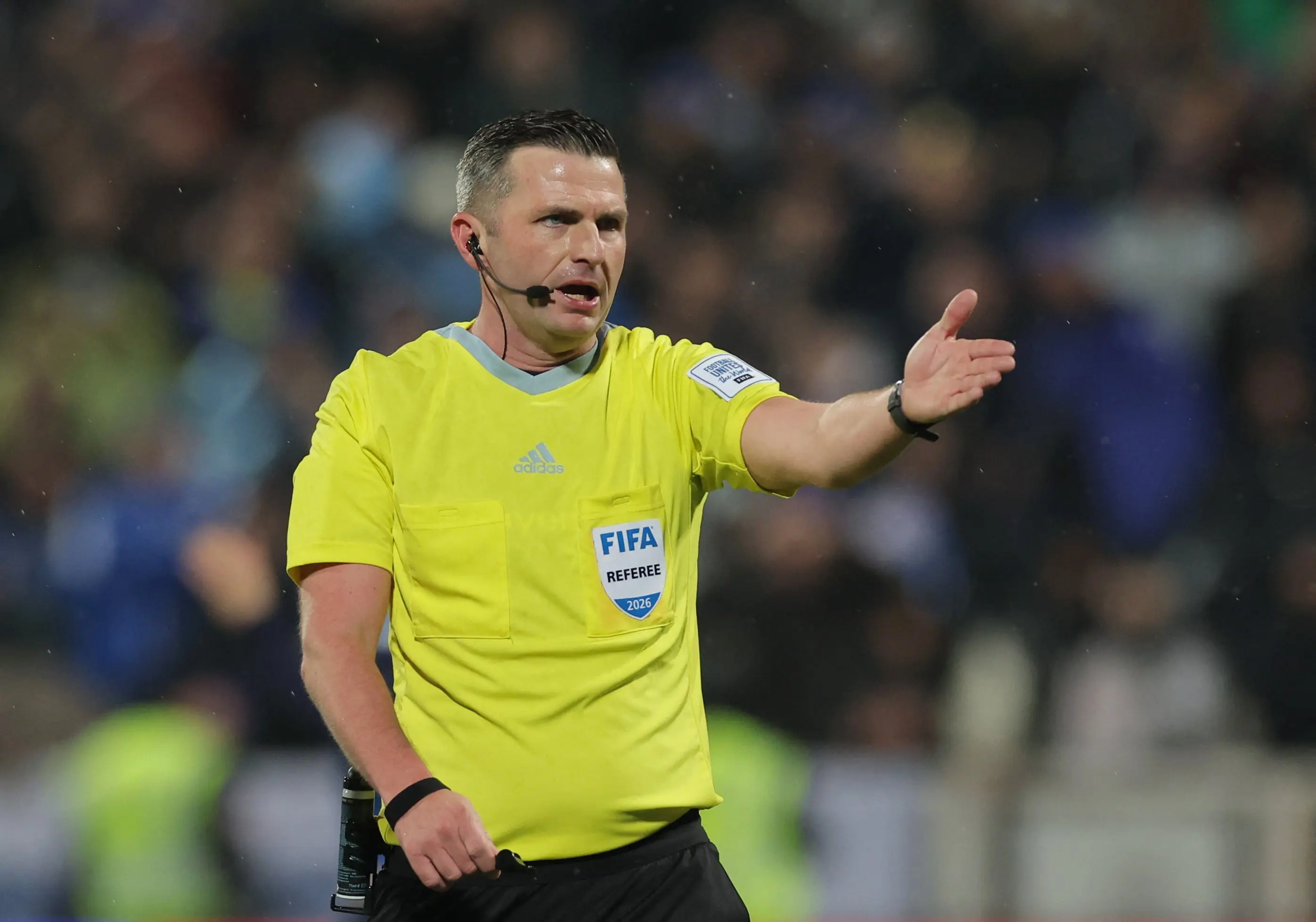 Soccer referee in yellow uniform signaling during a match.