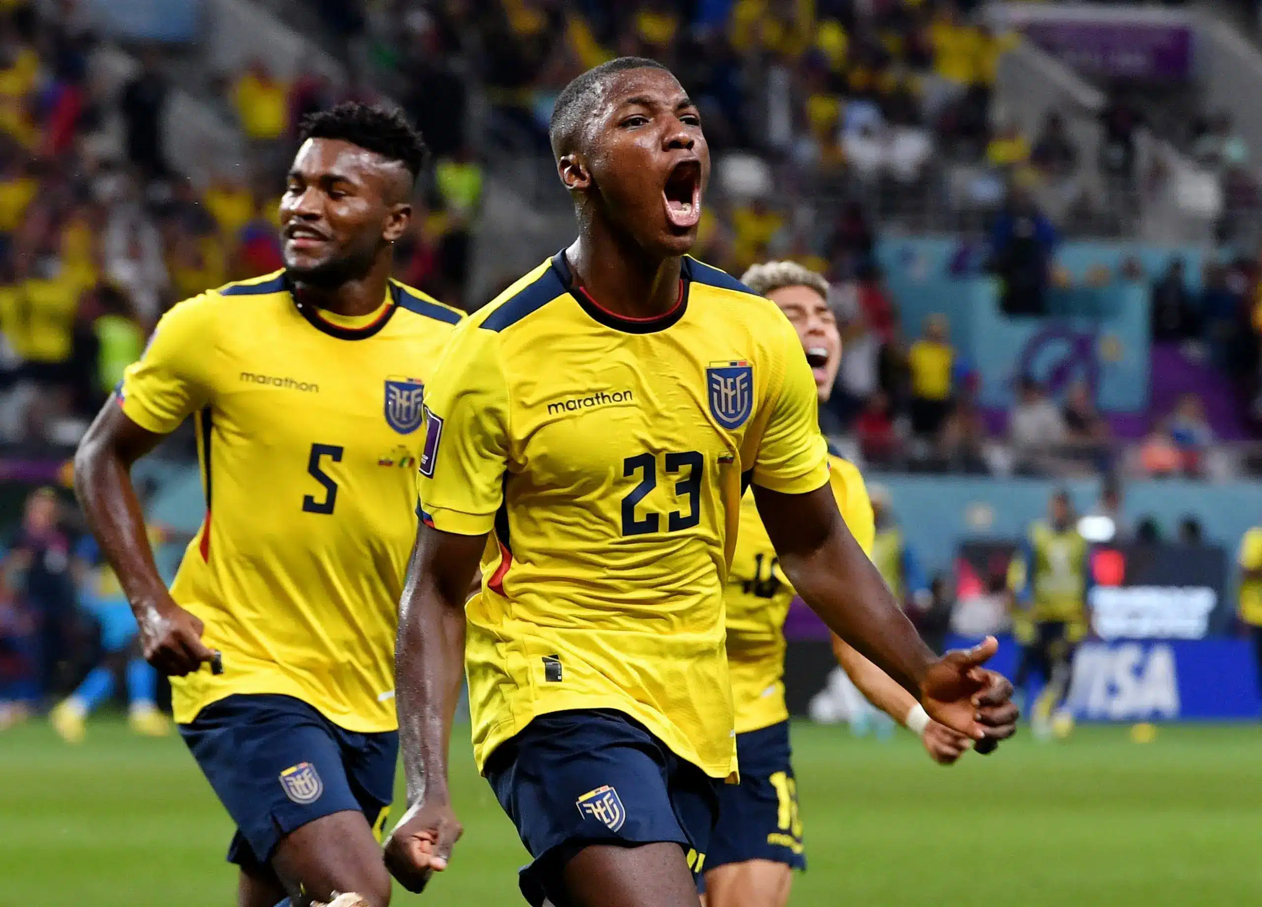 Ecuador football players celebrating a goal, wearing yellow jerseys.