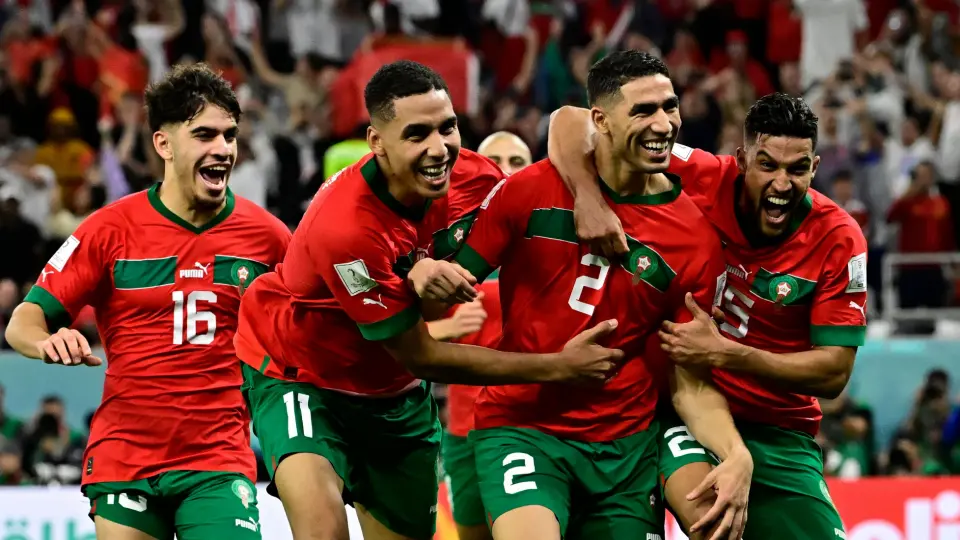 Morocco national football team players celebrating a victory, wearing red jerseys.