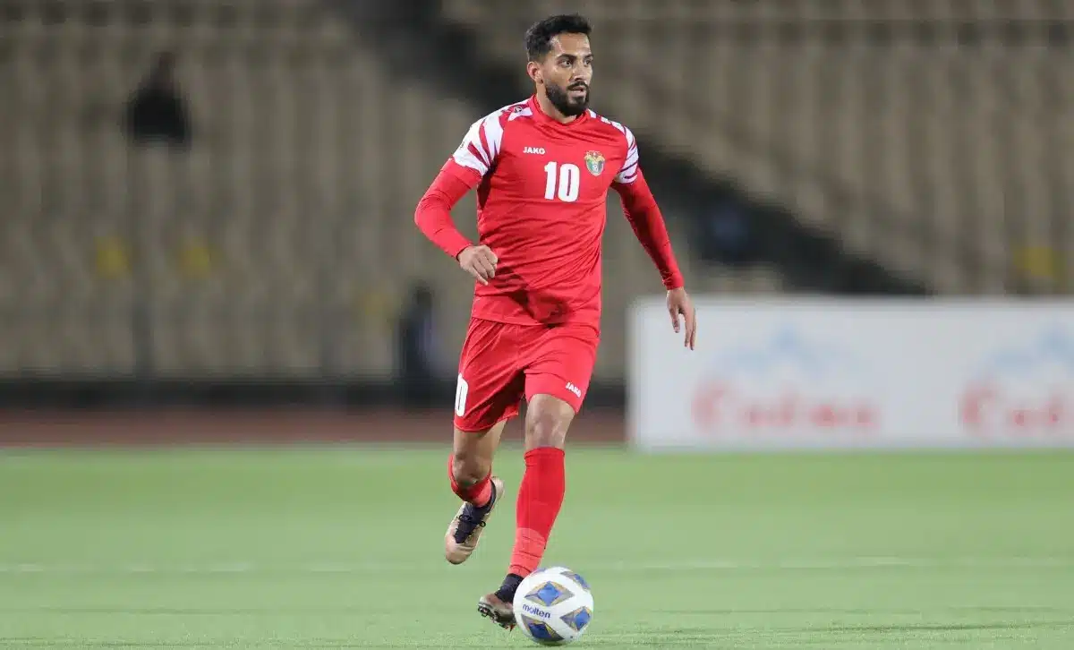Musa Al-Taamari running with the ball during a soccer match in Jordan's national team kit.
