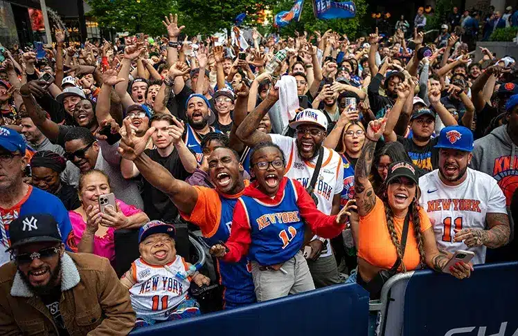 Crowd of enthusiastic New York Knicks fans celebrating with jerseys and banners.