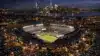Aerial view of illuminated MetLife Stadium at night with New York City skyline in background