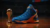 Blue and orange basketball sneaker on hardwood court with championship lighting