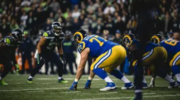 LA Rams offensive lineman in blue jersey at line of scrimmage in three-point stance during NFL game