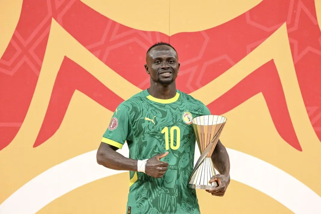 Sadio Mané celebrating with a trophy in Senegal football kit.