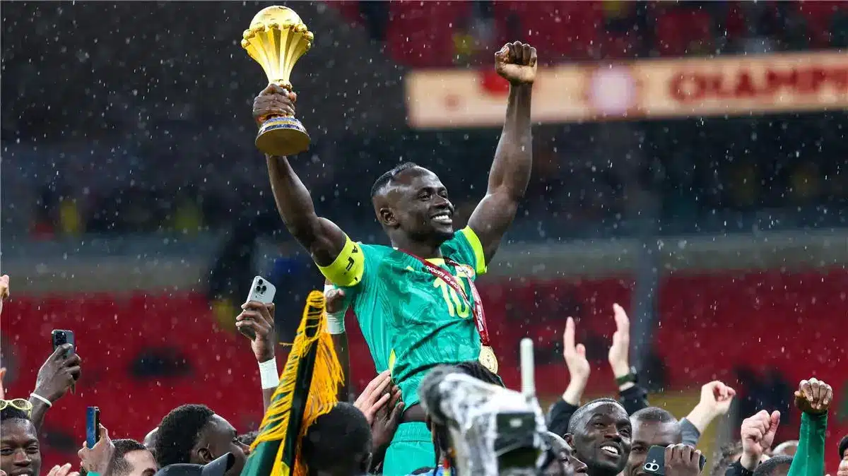 Sadio Mane celebrating Senegal's AFCON victory, holding the trophy in a stadium.