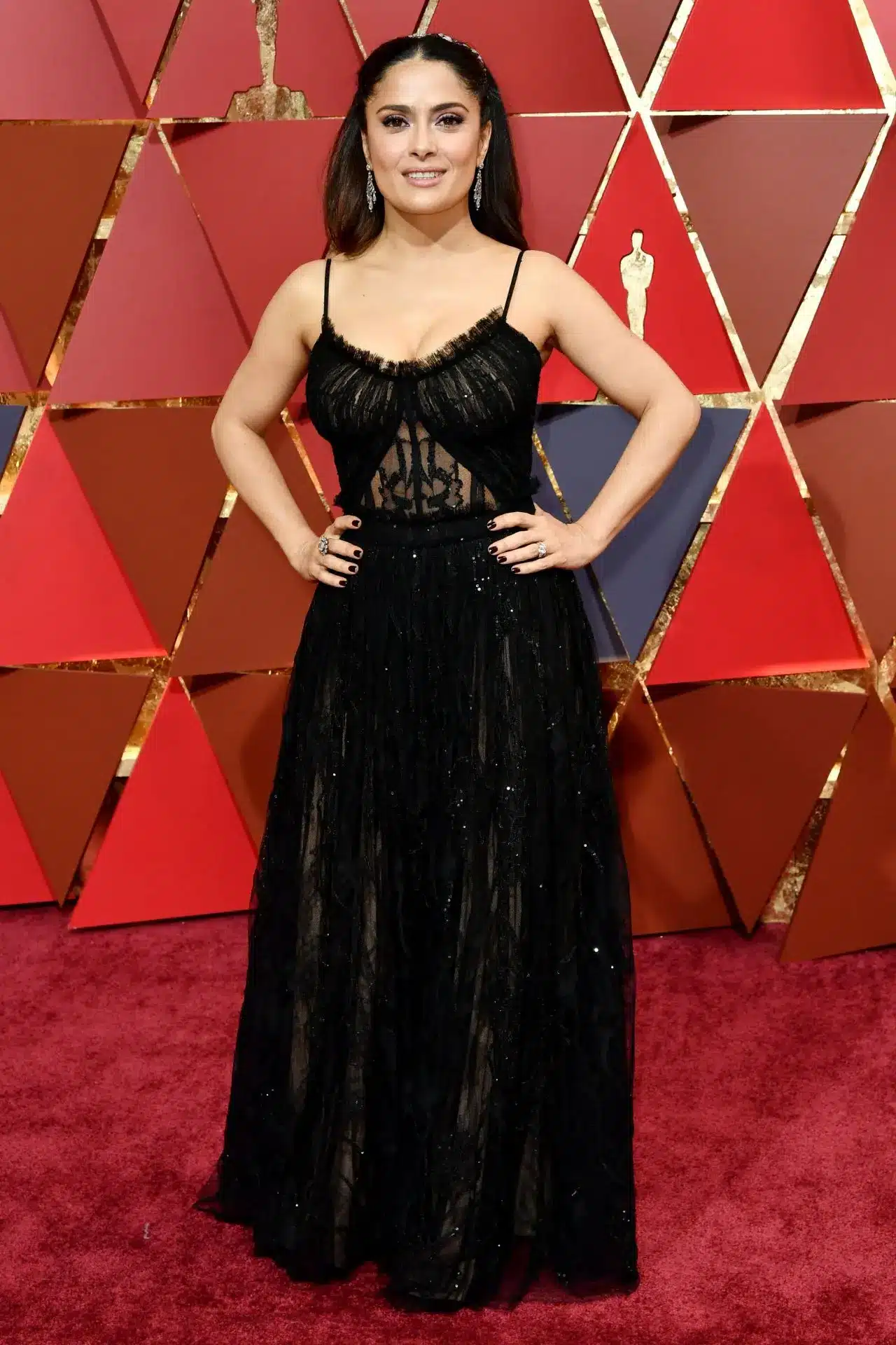 Salma Hayek on the red carpet in a black dress at an awards ceremony.