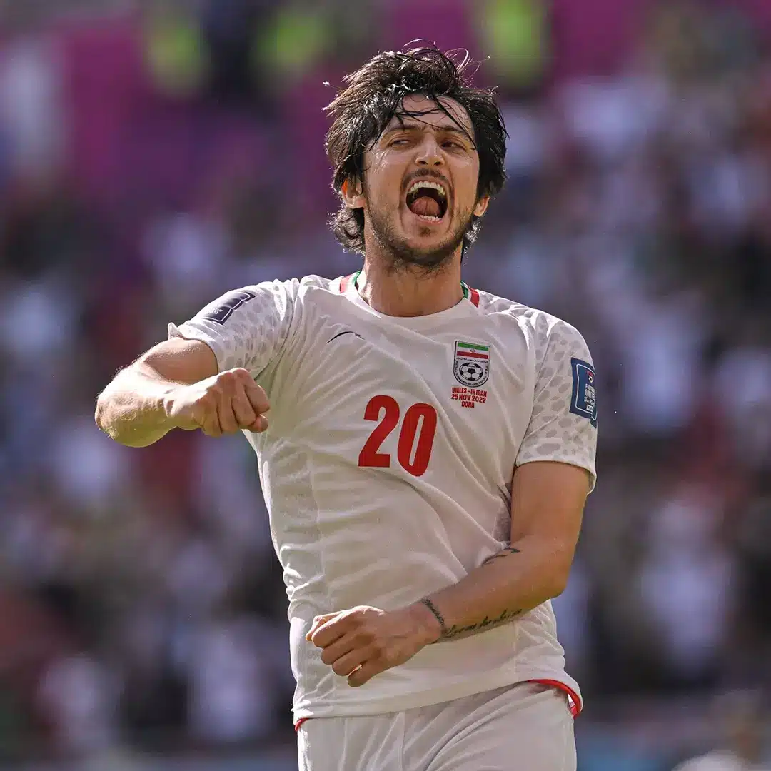 Sardar Azmoun celebrating during a match wearing the Iran national football team jersey.