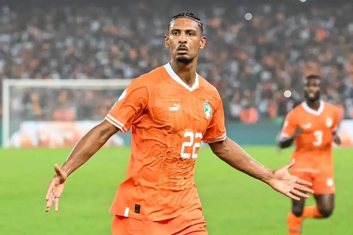 Sebastien Haller celebrating in an orange Ivory Coast football kit.