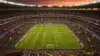 Aerial view of packed World Cup stadium at dusk with international flags and dramatic floodlights