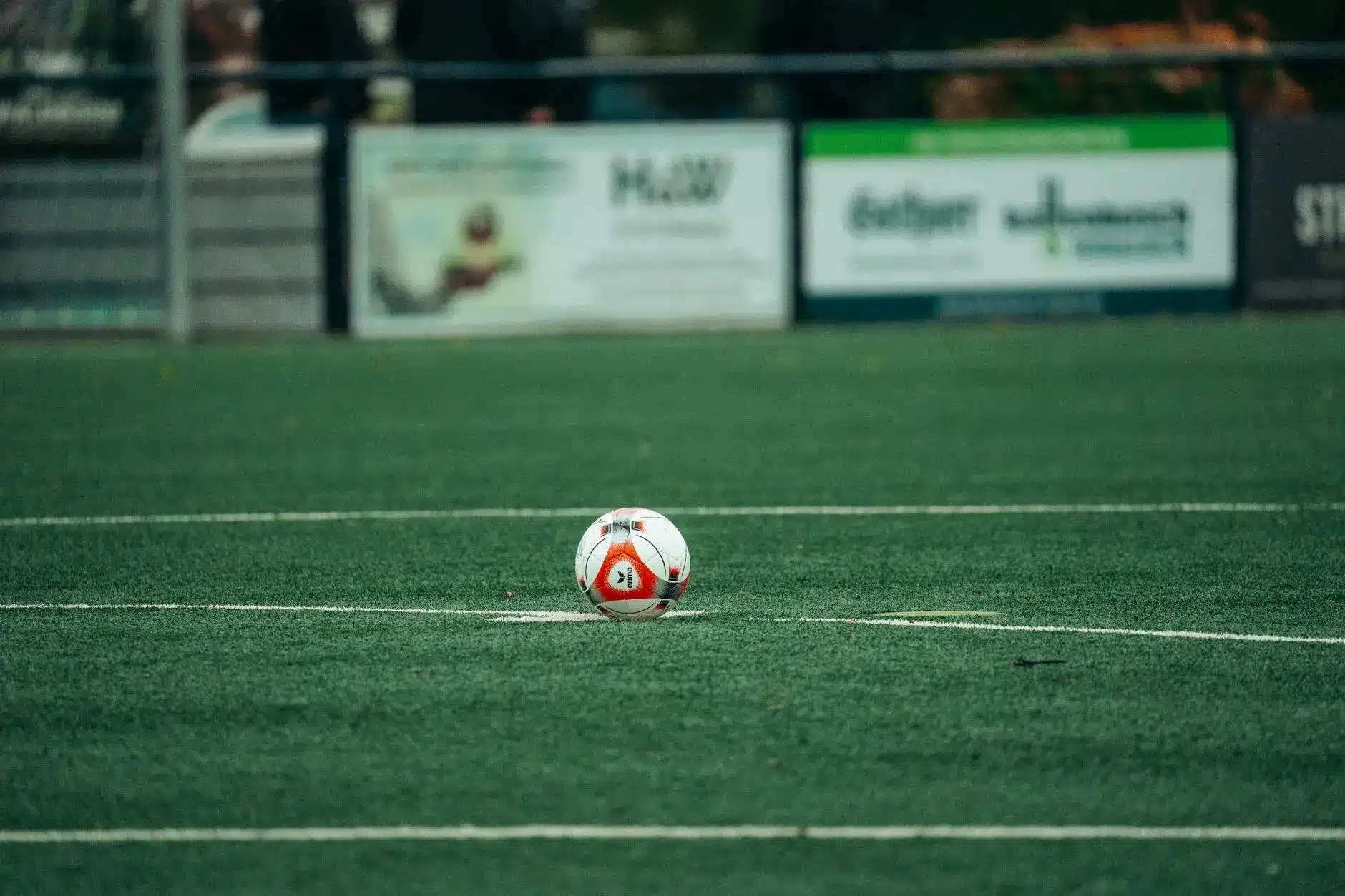 A soccer ball positioned on grass turf at a stadium.