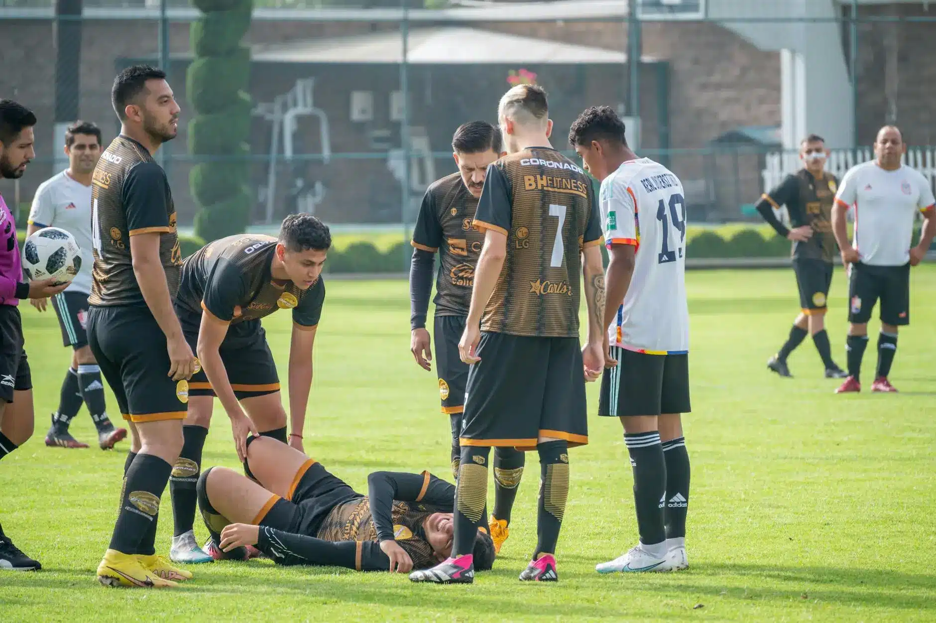 Soccer players attending to an injured teammate lying on the field.