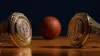 Two NBA championship rings gleaming in dramatic lighting with basketball in background