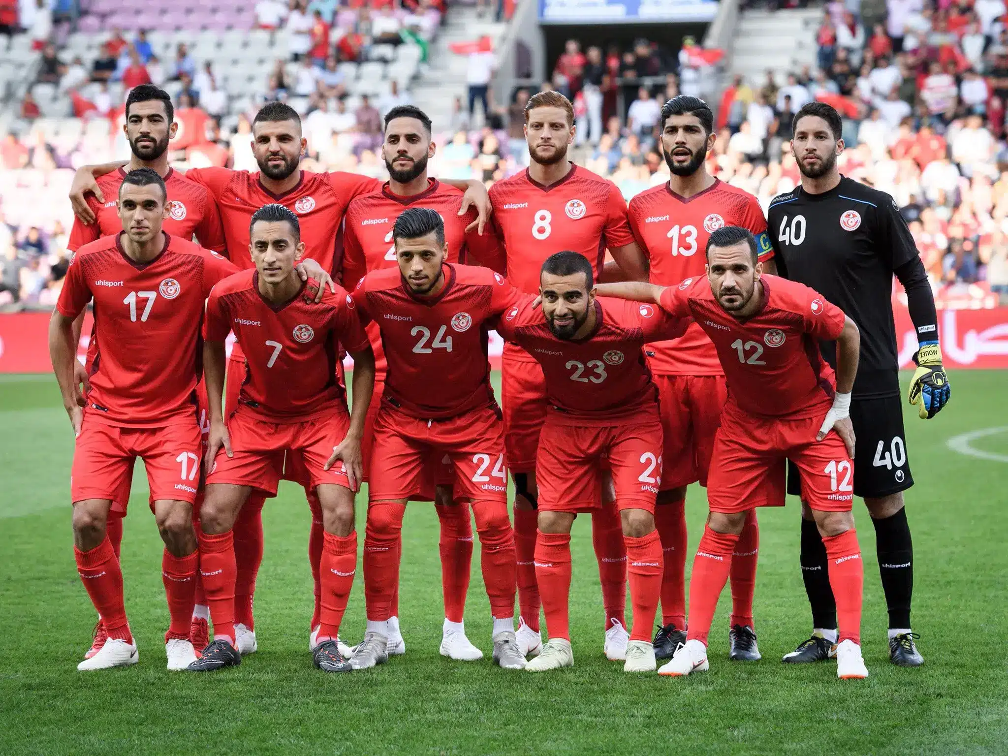 Tunisia national football team posing for a group photo in red jerseys.