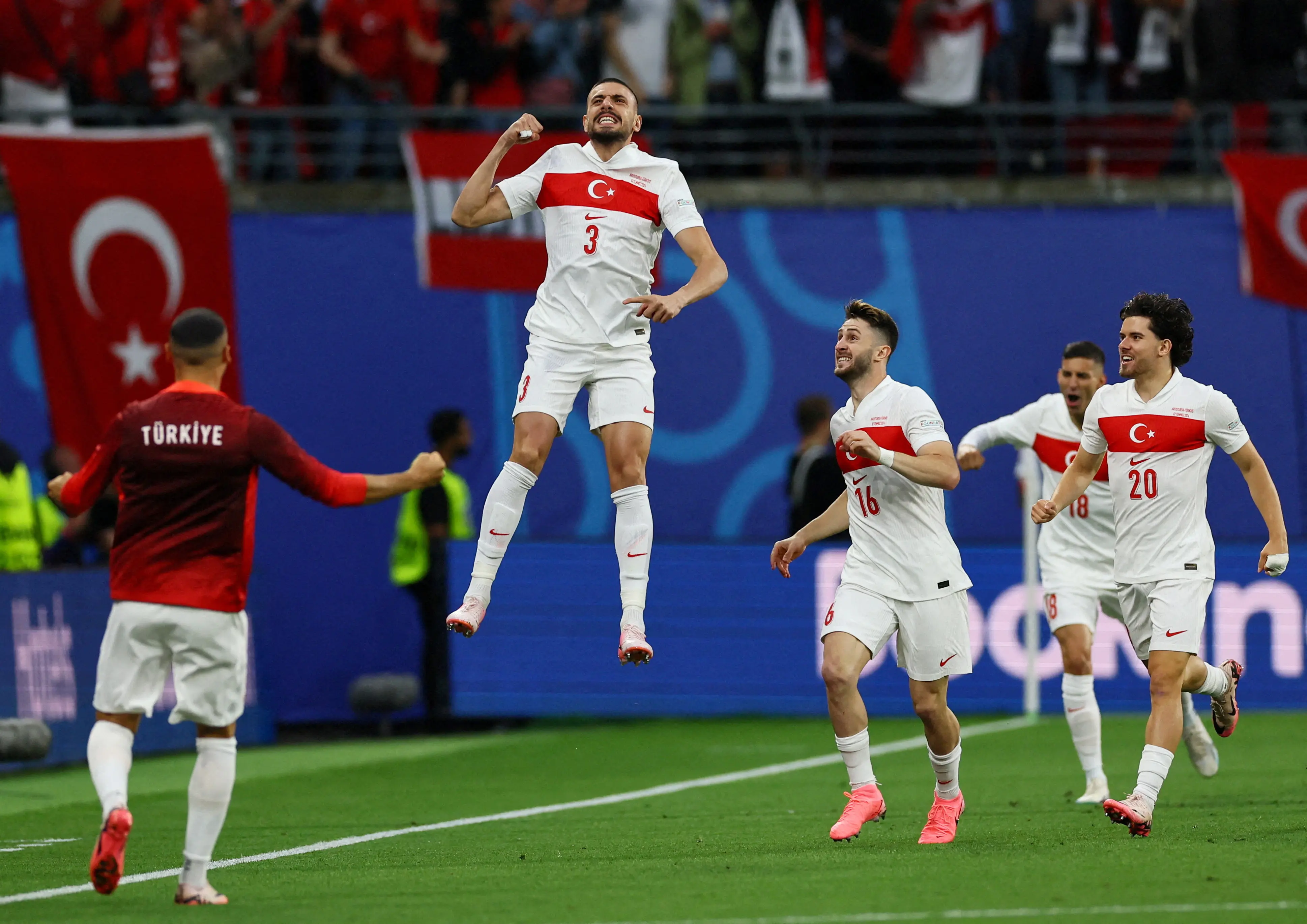 Turkish football players celebrating a goal with flags in the background.
