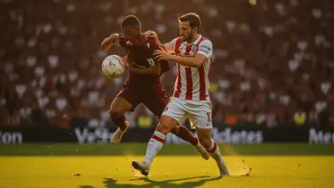 Two soccer players battling for ball possession in intense World Cup match under stadium lights