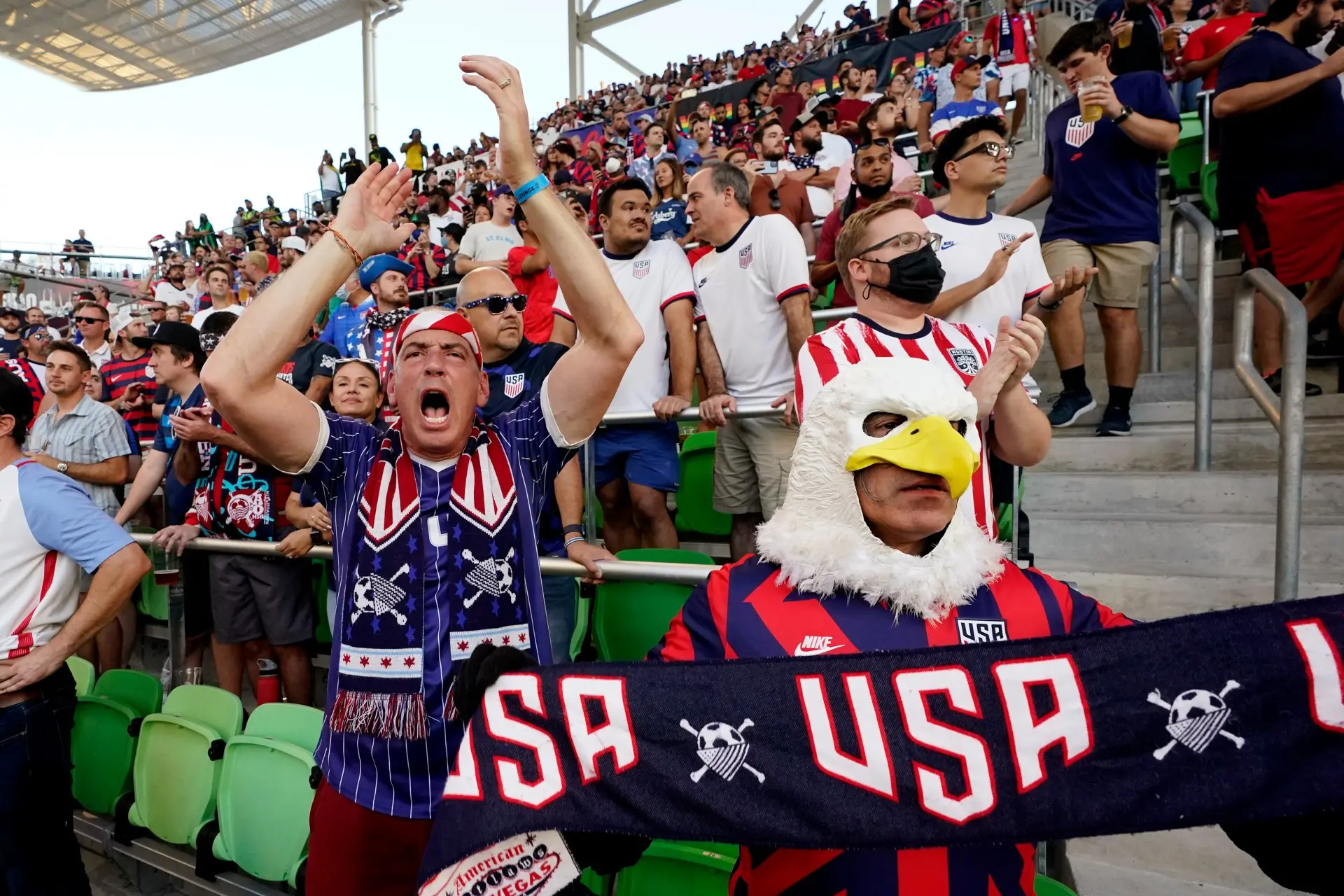 USA soccer fans cheering in stadium, wearing team colors and accessories.