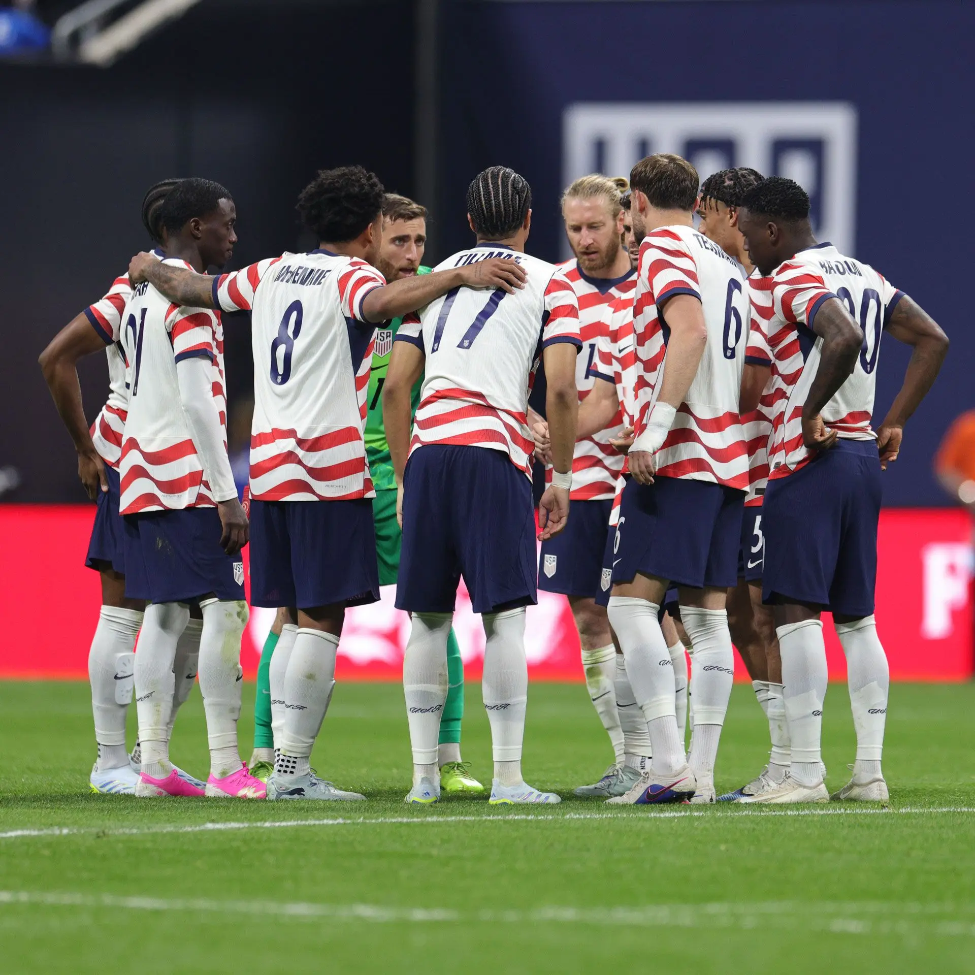 USMNT players huddled together on the field during a match.