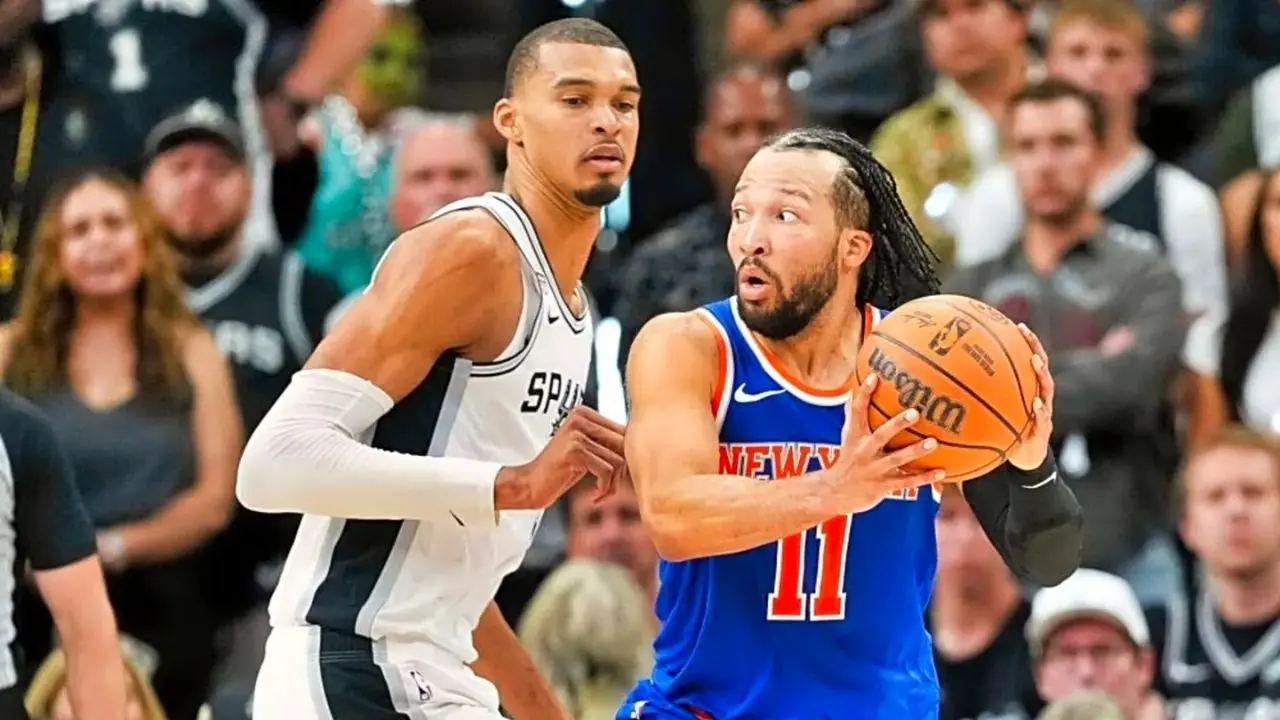 Jalen Brunson wearing a Knicks jersey dribbling the ball, with Victor Wembanyama in defense.