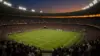 Illuminated World Cup soccer stadium at twilight with packed crowd and vibrant atmosphere