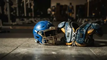 NFL football helmet and pads on training facility floor in dramatic lighting