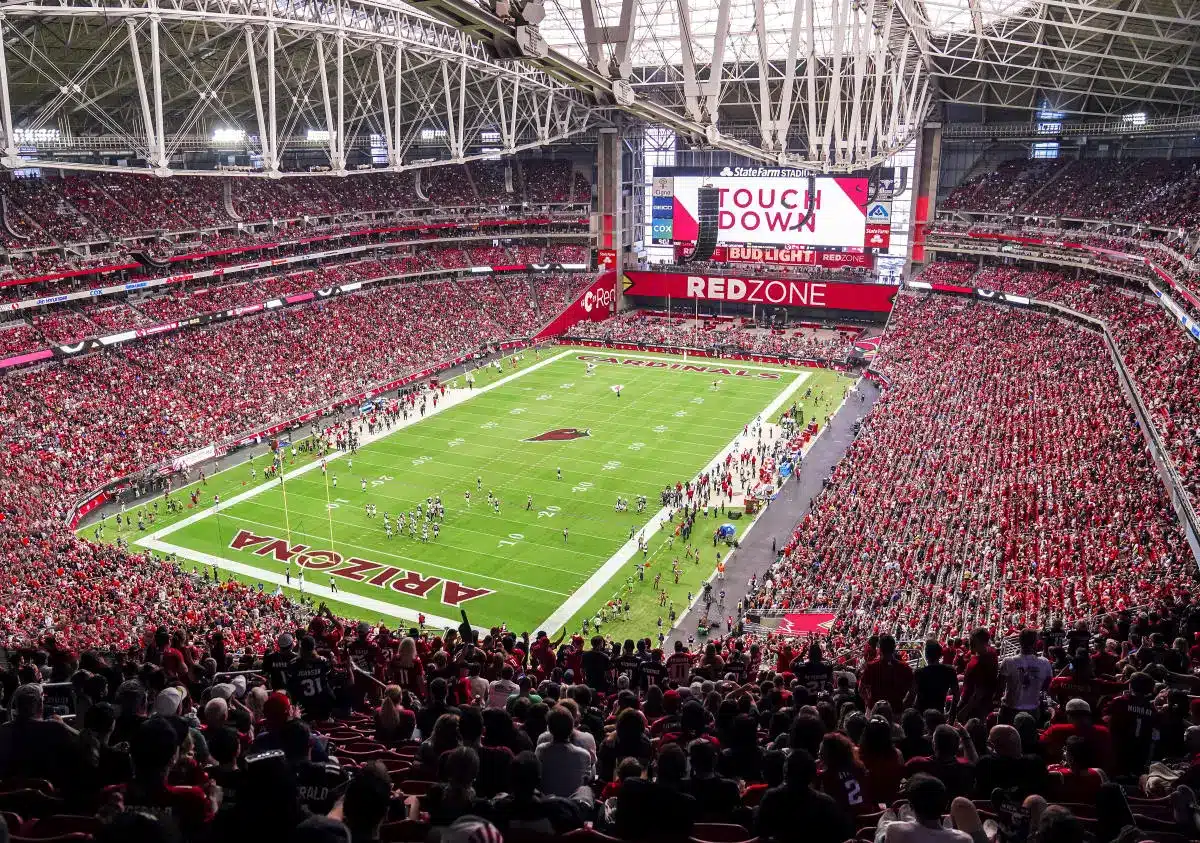 Packed State Farm Stadium during an Arizona Cardinals game with fans in red.