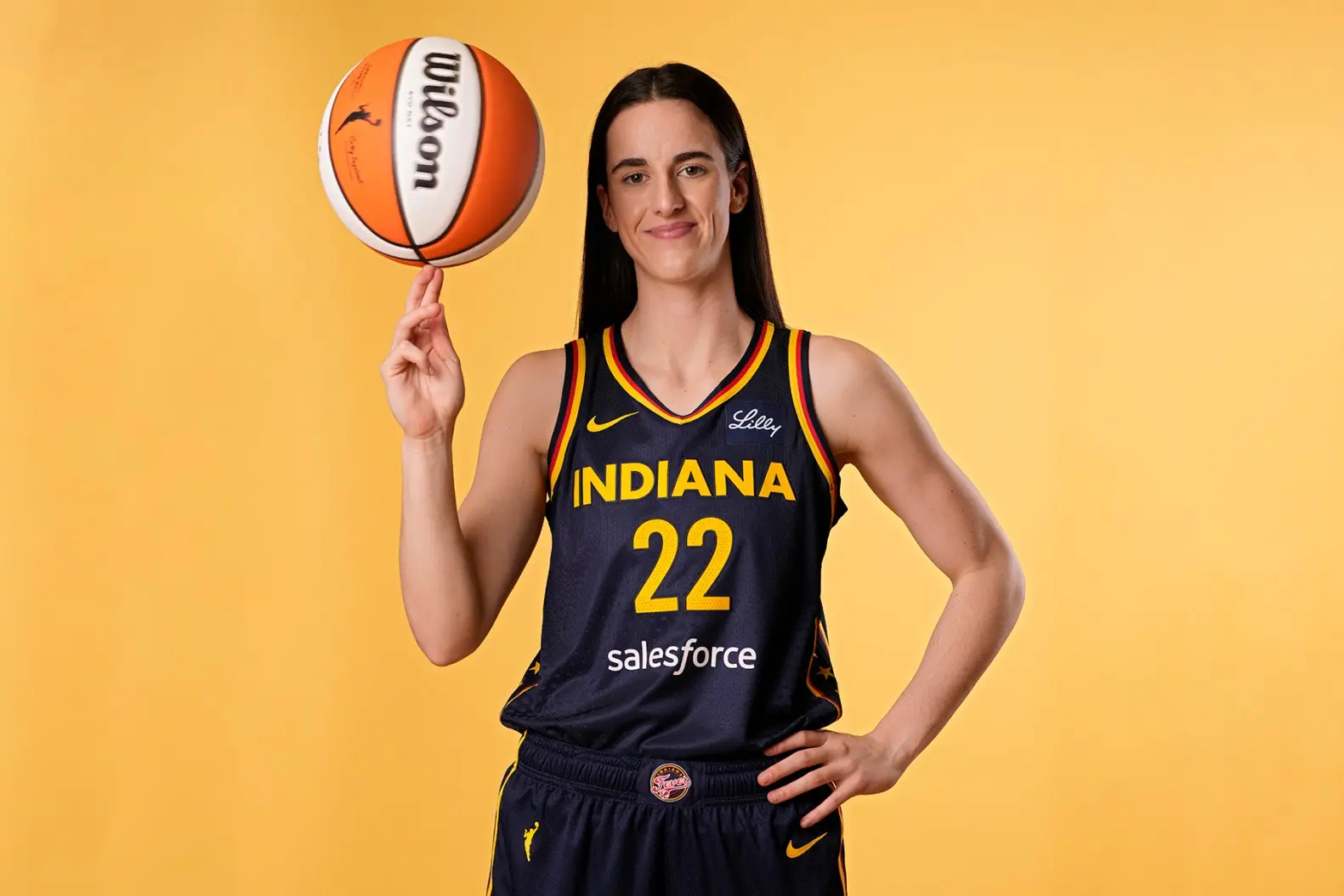 Player spinning a basketball on her finger, wearing an Indiana Fever jersey.