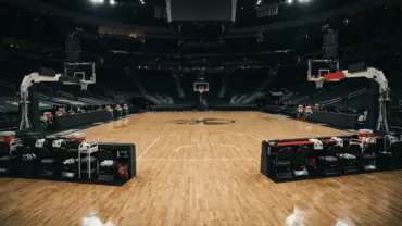 NBA basketball court with two team benches showing competing colors in dramatic arena lighting
