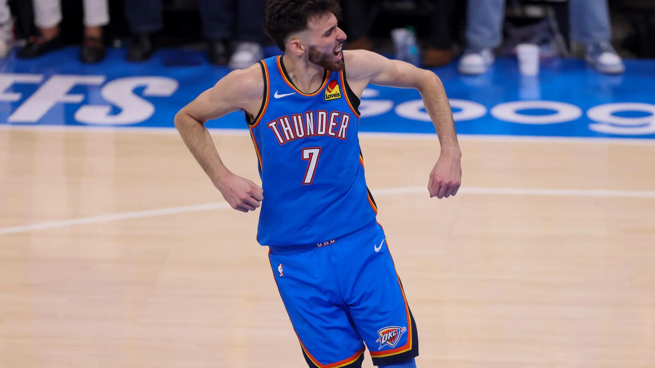 Chet Holmgren in a blue Oklahoma City Thunder jersey celebrating on the basketball court.