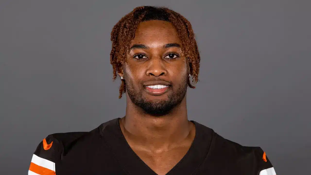 Headshot of Denzel Ward wearing a brown Cleveland Browns jersey against a grey background
