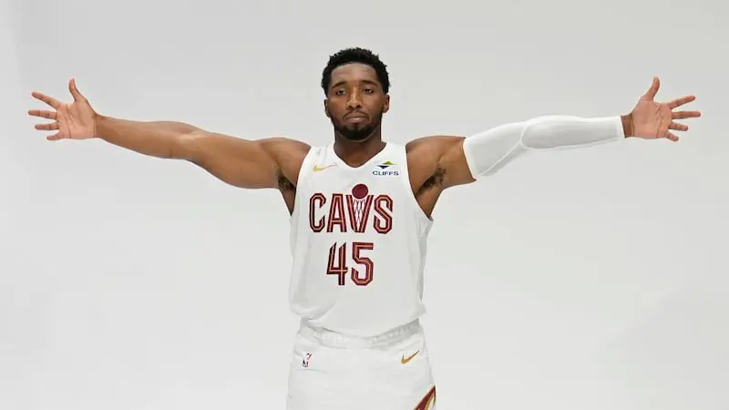 Donovan Mitchell wearing a white Cleveland Cavaliers jersey with the number 45, posing with arms outstretched.