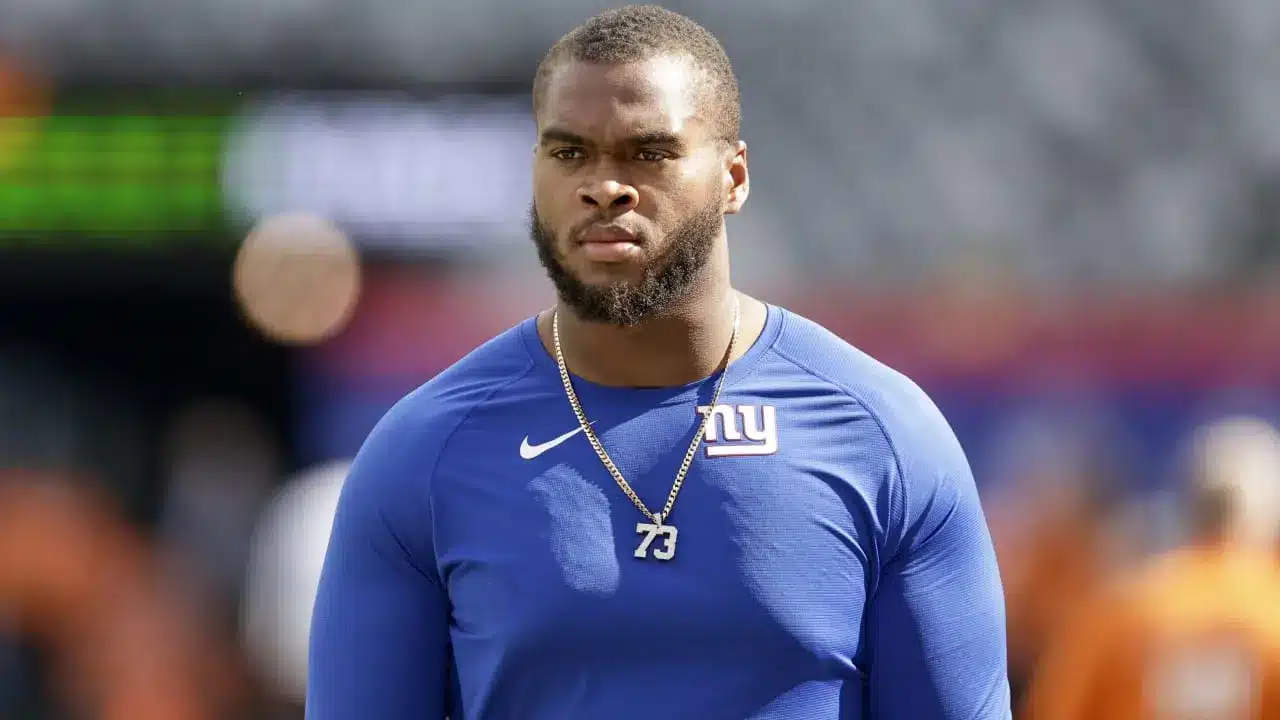 Evan Neal of the New York Giants in a blue jersey during warm-ups.