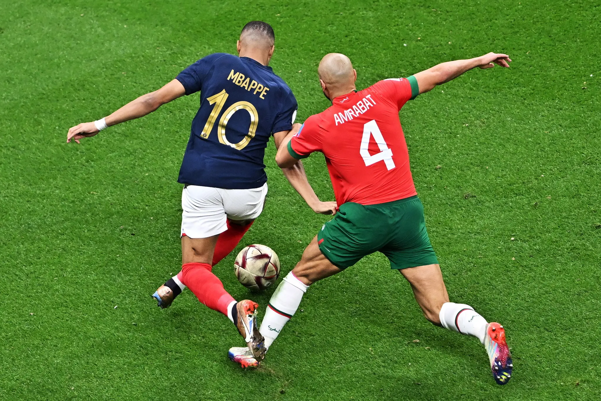 Two soccer players, Mbappe from France and Amrabat from Morocco, contesting for the ball.