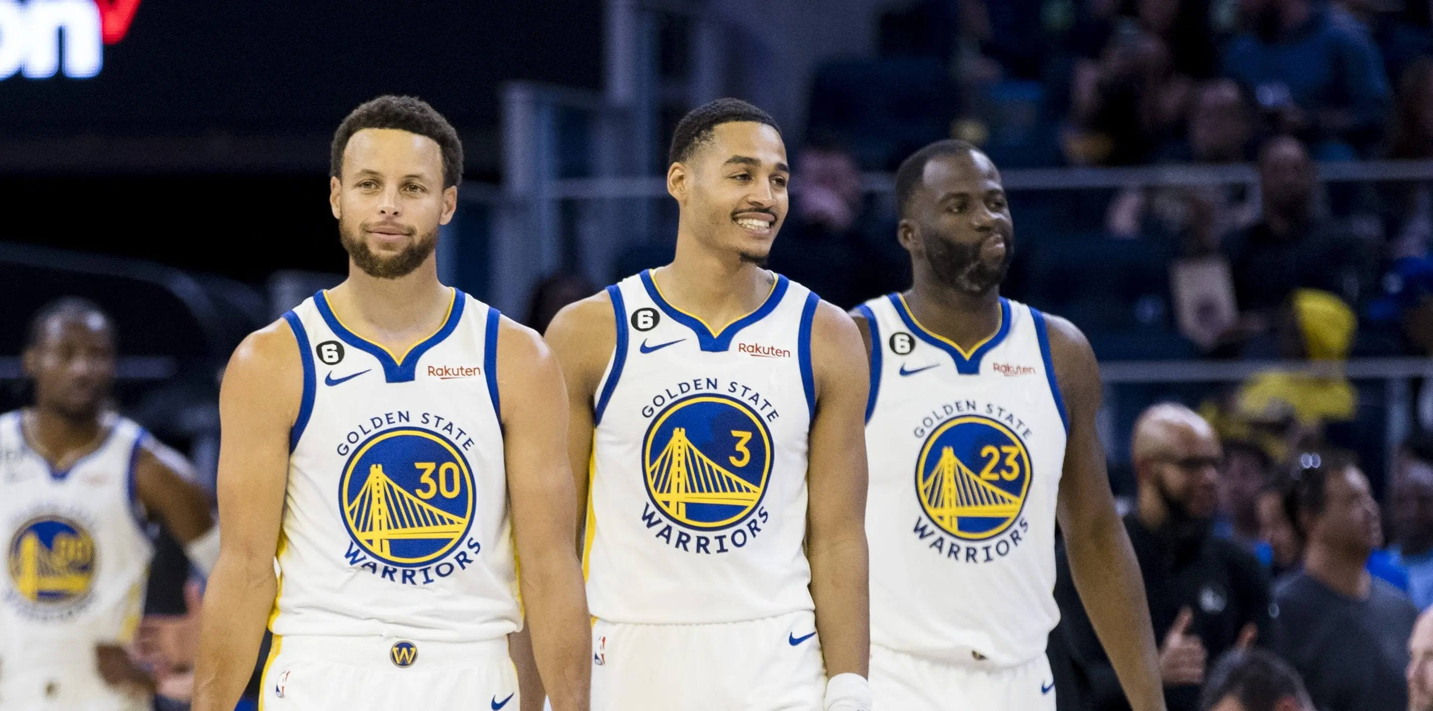 Three Golden State Warriors players in team jerseys during a game.