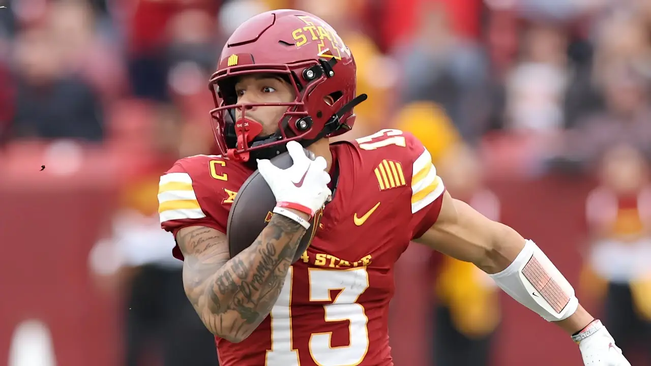 Football player in a red Iowa State uniform holding a football.