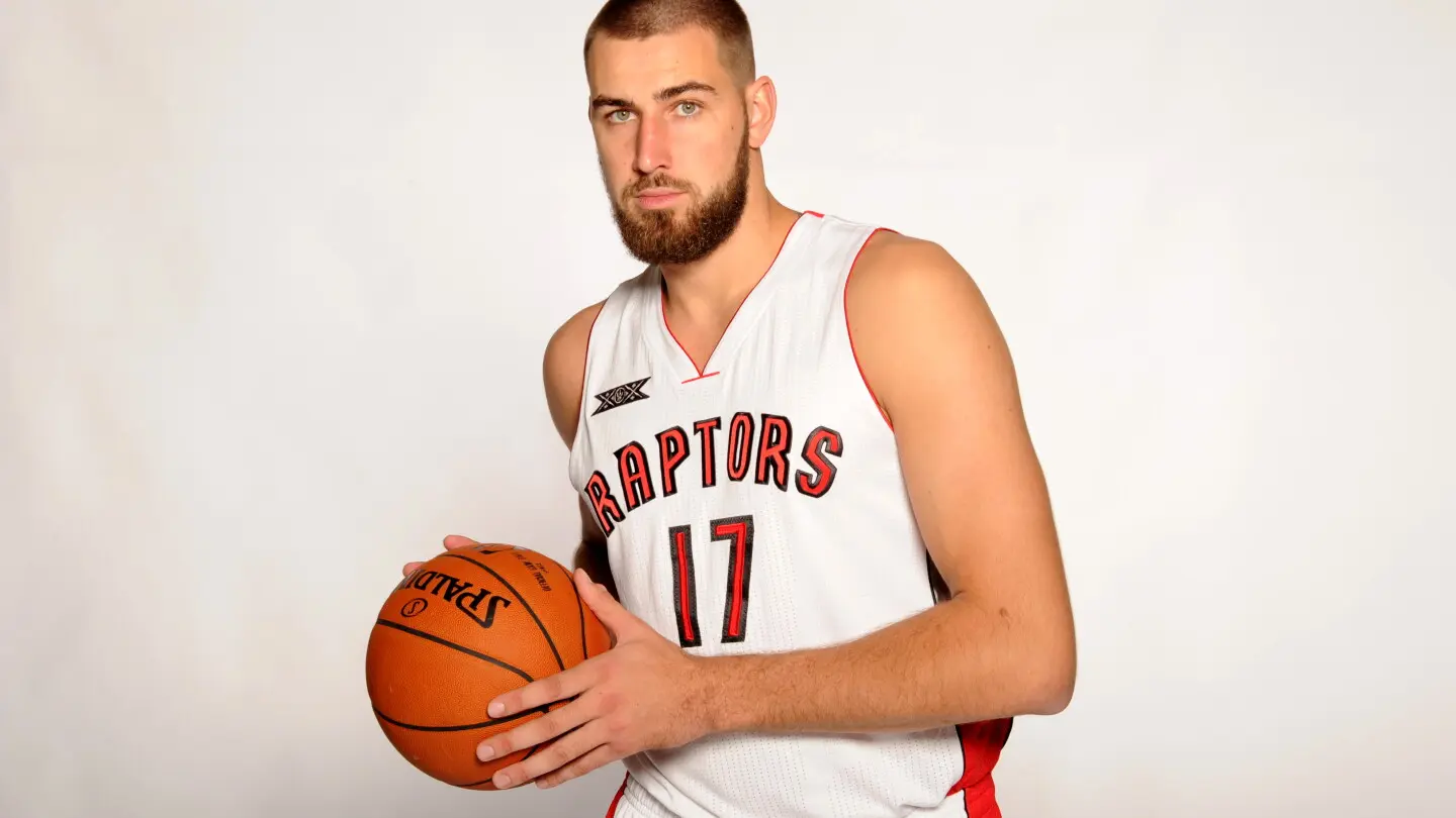 Jonas Valanciunas in a Toronto Raptors jersey holding a basketball.