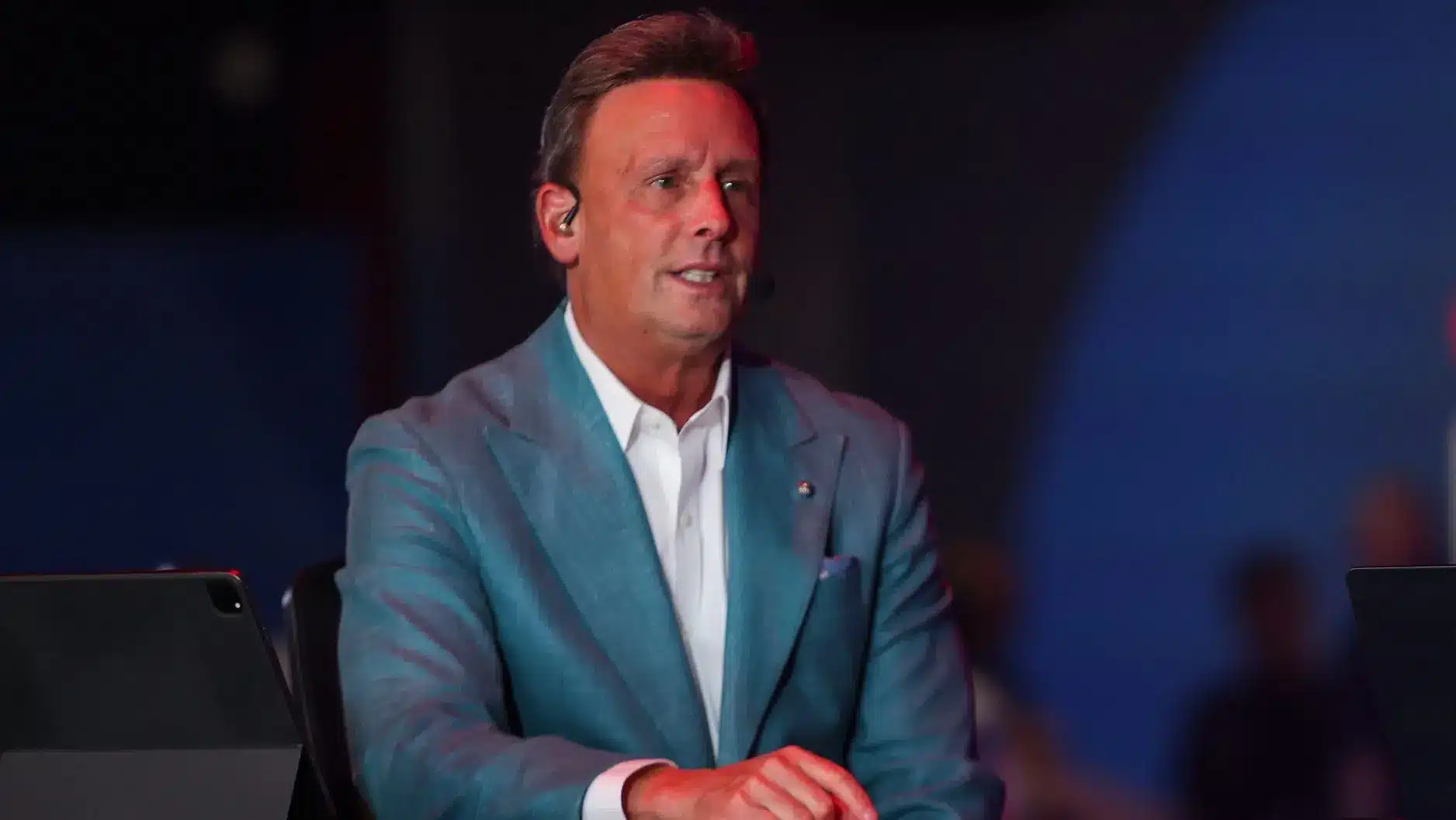 Karl Ravech, ESPN broadcaster, seated at a studio with a microphone.