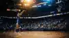 Basketball player in Warriors jersey shooting three-pointer in arena with dramatic lighting