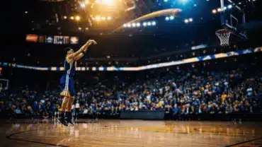 Basketball player in Warriors jersey shooting three-pointer in arena with dramatic lighting