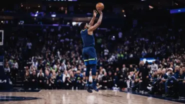 Minnesota Timberwolves player taking jump shot in arena with dramatic lighting