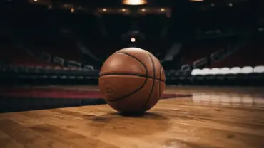 Basketball on hardwood court with Miami Heat colors and dramatic arena lighting