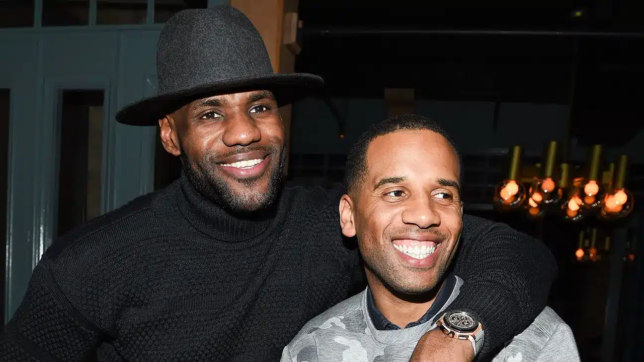 LeBron James wearing a black hat and turtleneck with his arm around Maverick Carter.